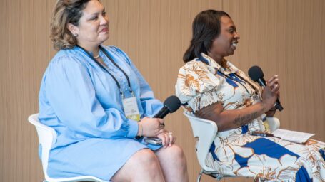 Two ladies sitting in chairs holding microphones.