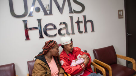 Father holding baby next to mother in a waiting room. 
